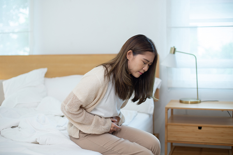 Woman holding her lower abdomen while experiencing abdominal pain after abortion surgery